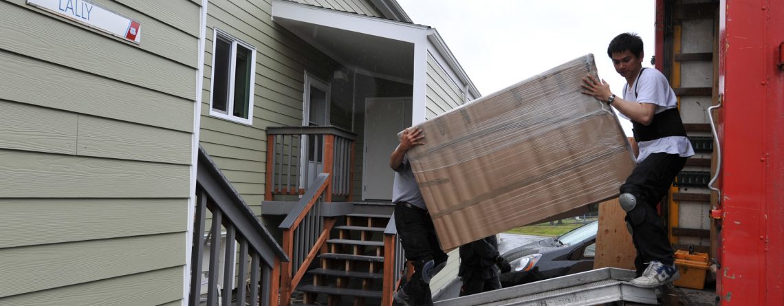 A man loading a moving truck in front of a house to celebrate Boxfactory's 90 years in business.