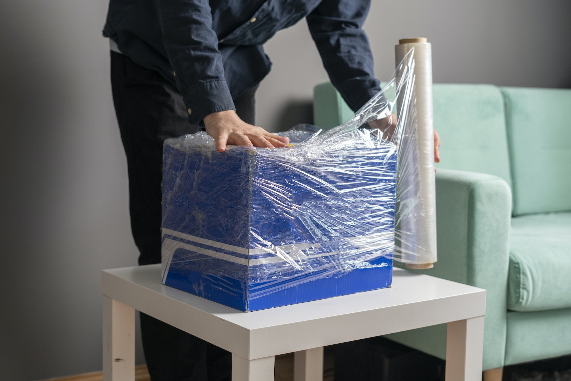 A man is wrapping a box with plastic wrap.