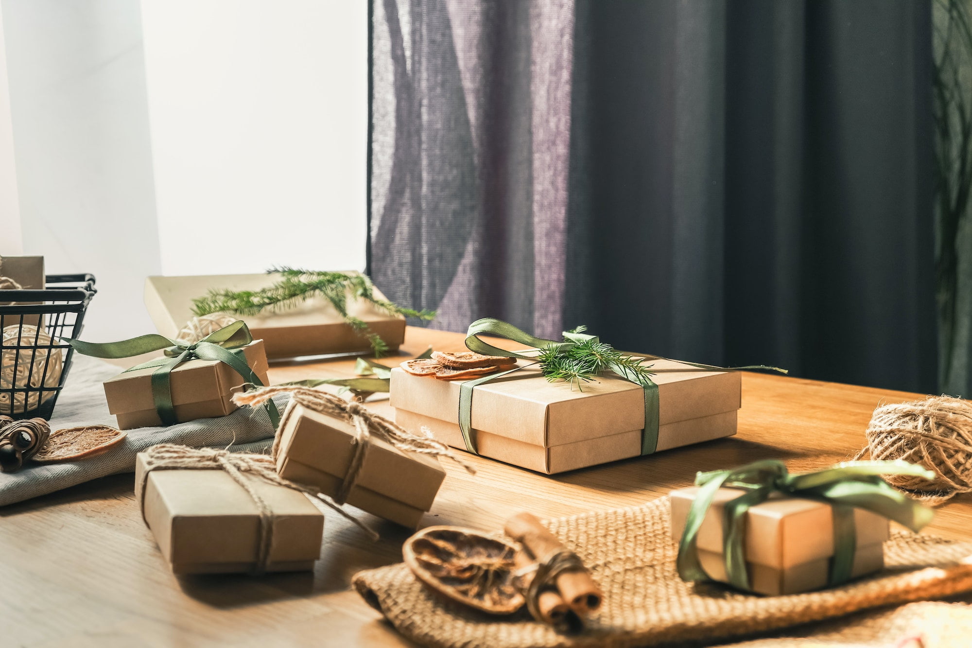 Christmas gifts on a wooden table in front of a window.