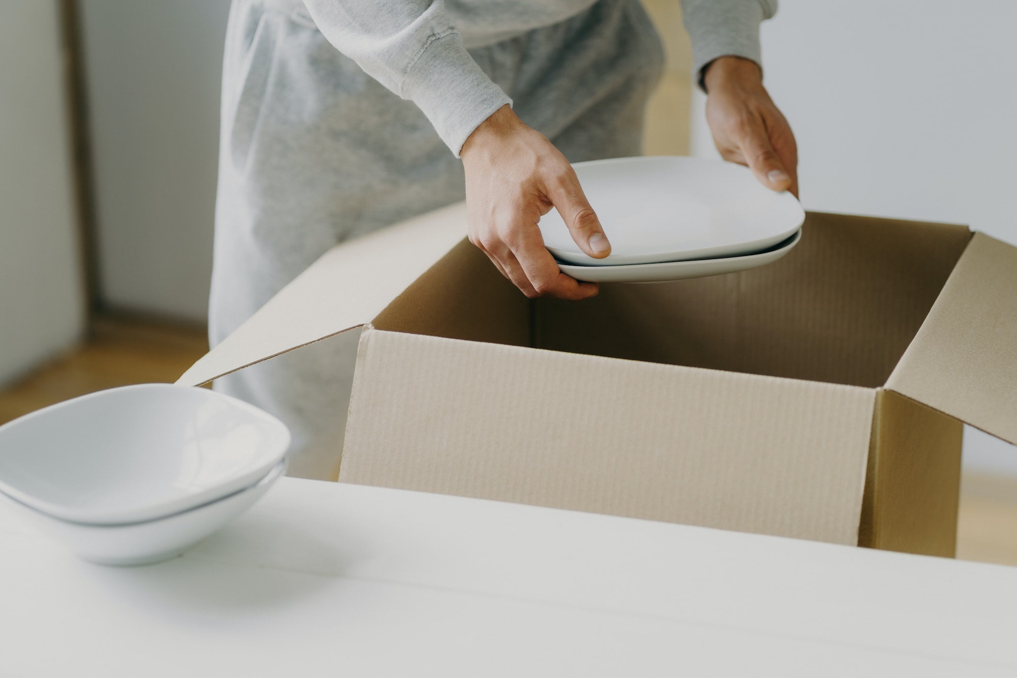 A woman is opening a cardboard box with a plate inside.