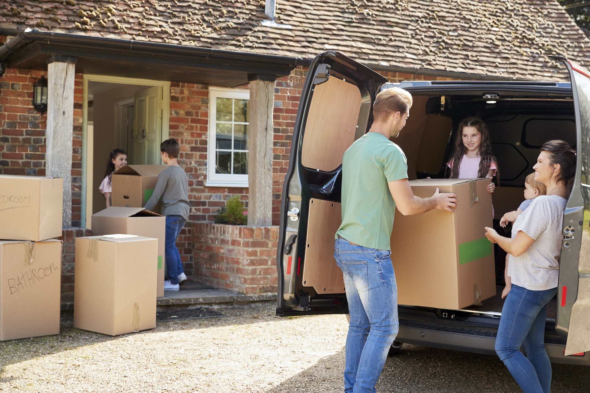 A group of people loading boxes into a van in front of a house.