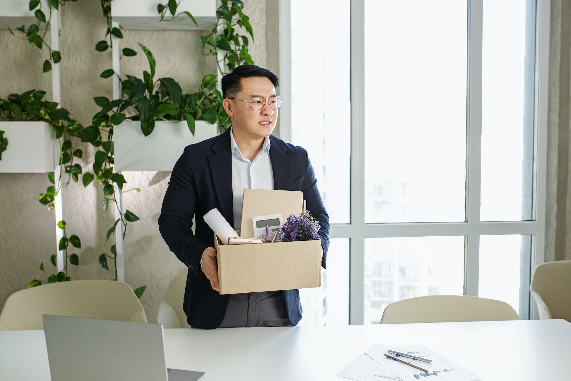 Asian businessman holding a box in an office.