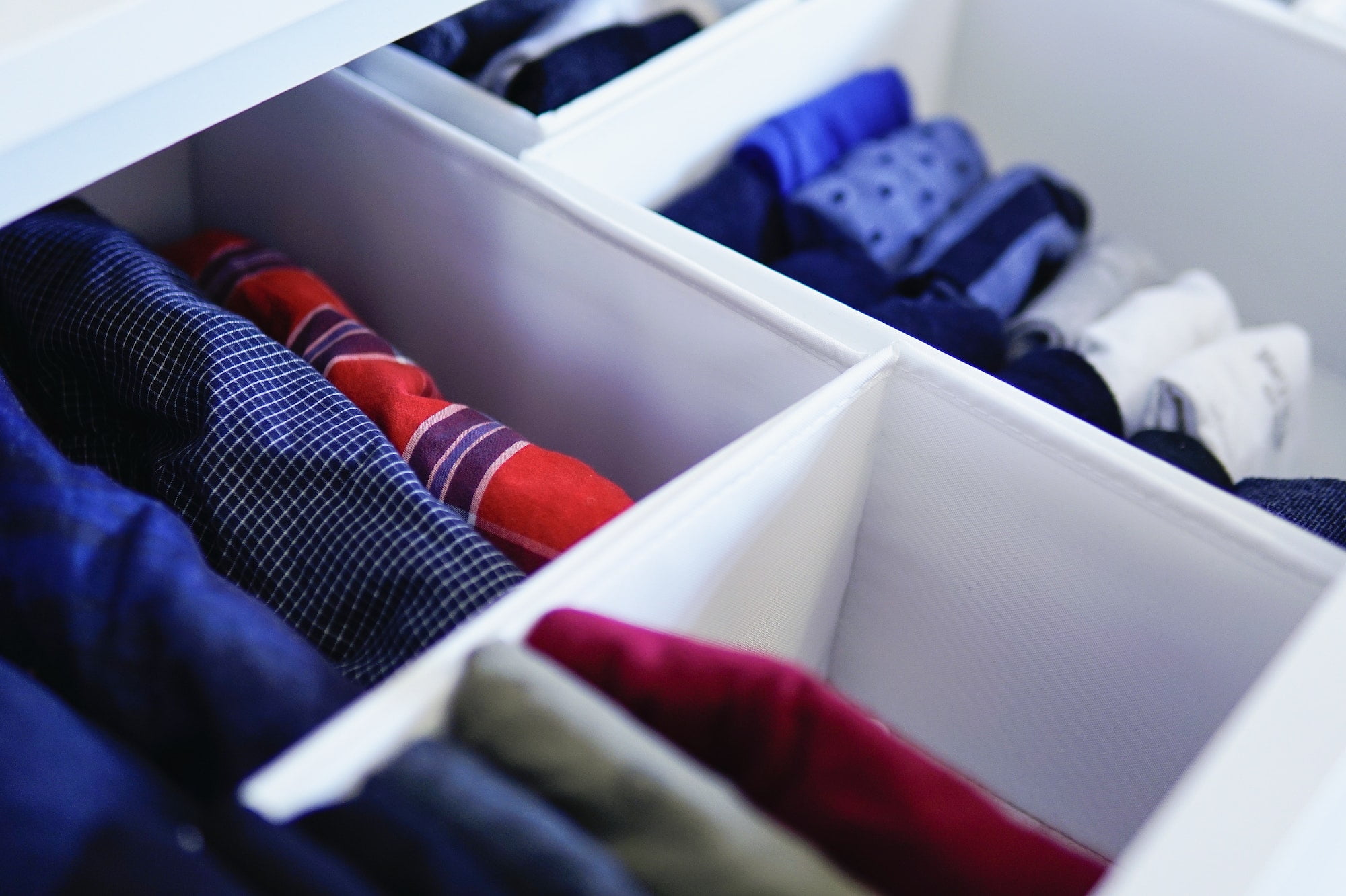 A drawer full of clothes in a white closet.