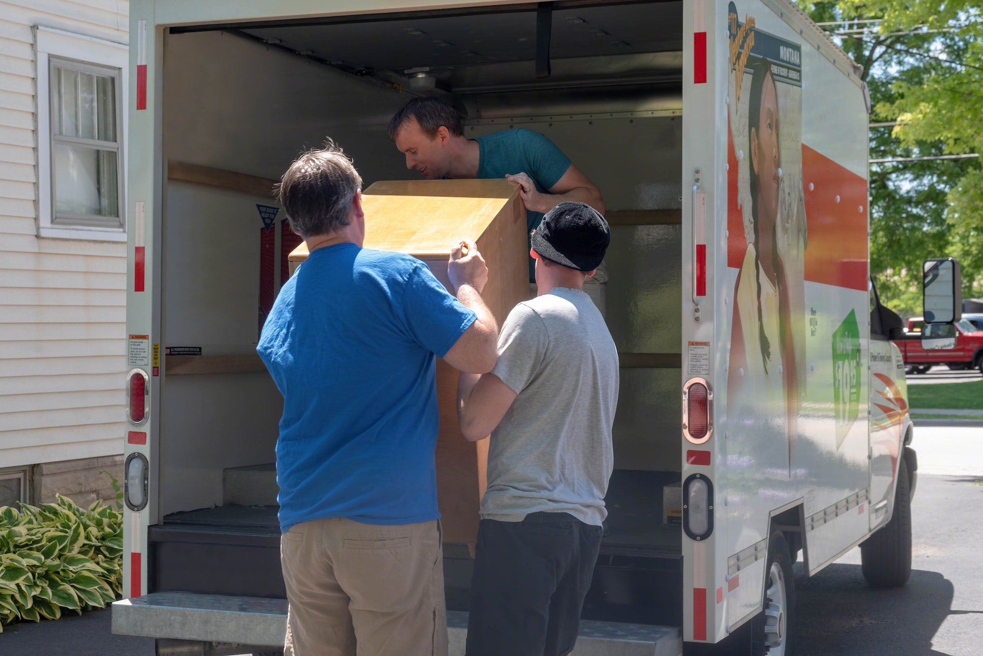 Three men loading boxes into a moving truck.