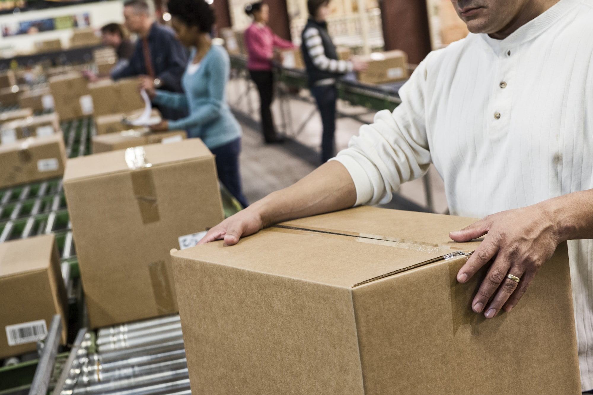 A man is holding boxes in a warehouse.