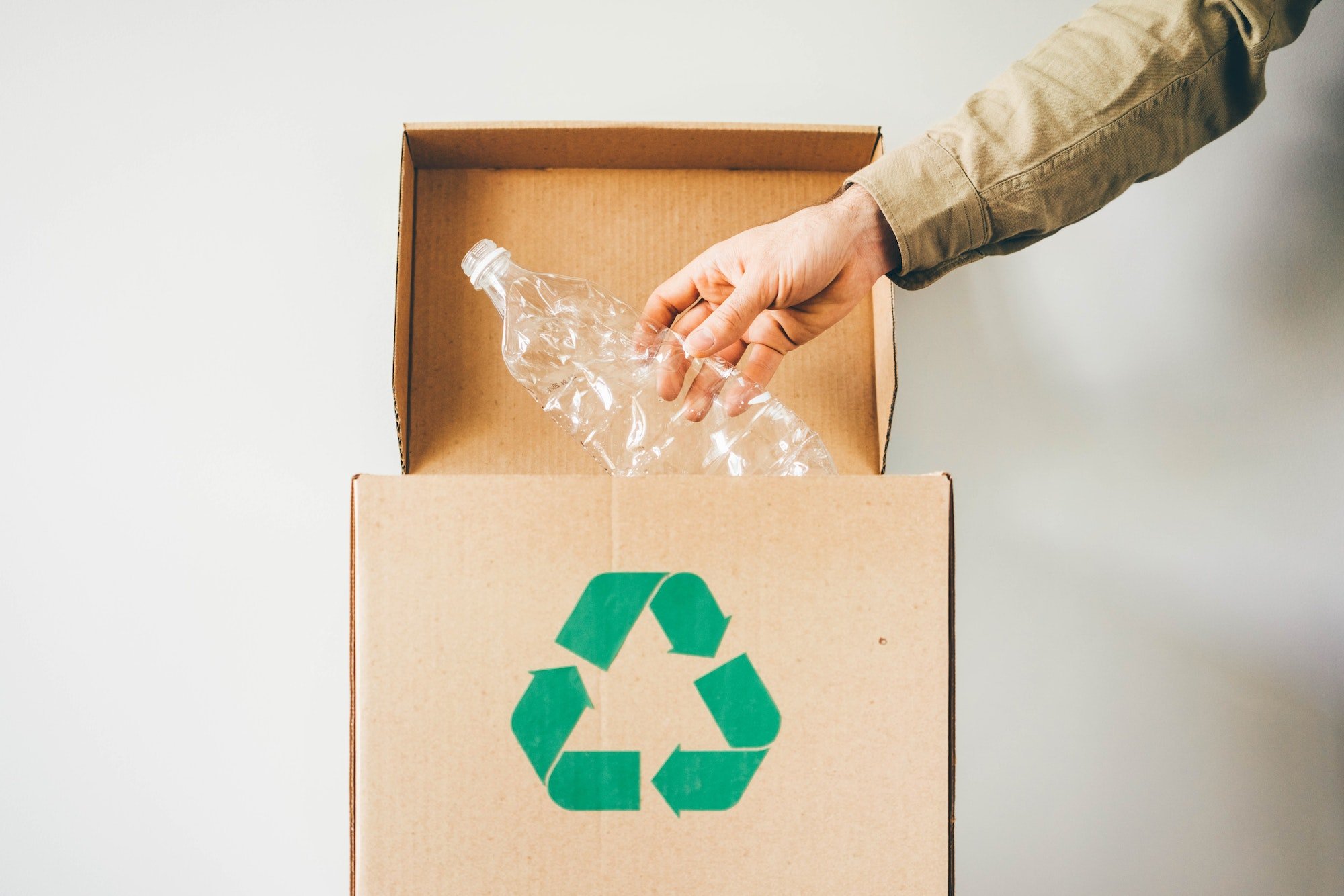 A person is putting a recycling bin into a cardboard box.