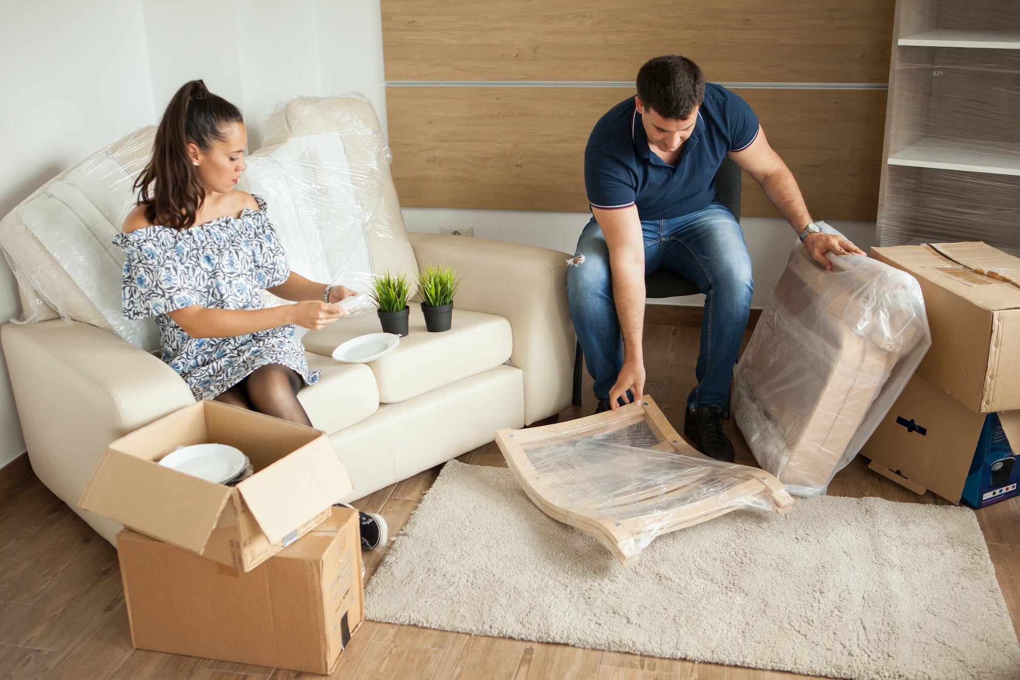 A man and woman unpacking boxes in a living room.