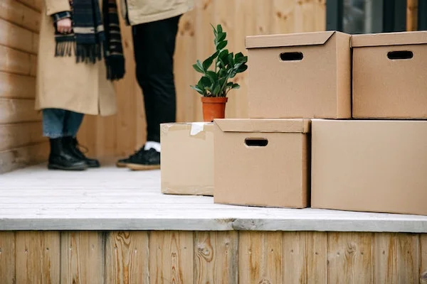 Two people sorting cardboard boxes on a porch.
